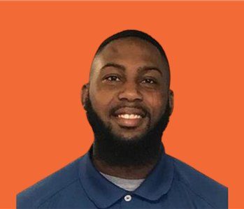 Production Technician Edgar smiles in front of orange background