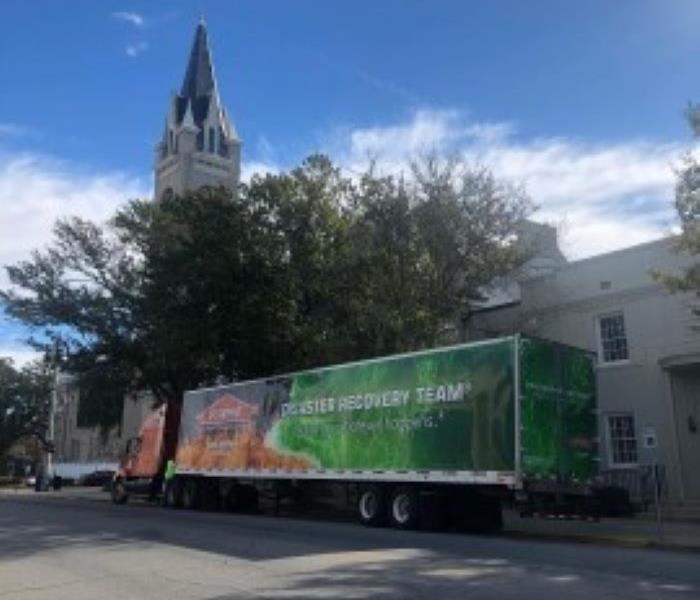 A large green SERVPRO truck is shown in front of a church