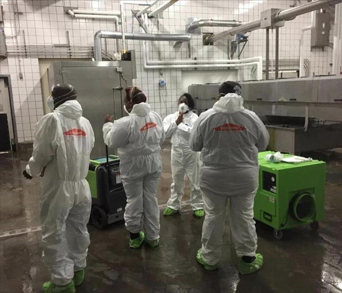 SERVPRO technicians in protective gear are shown on a job